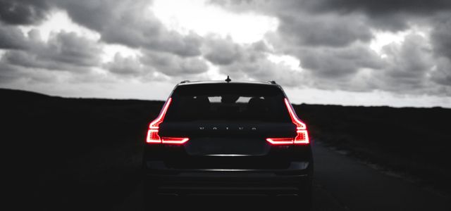 red car on black asphalt road under gray cloudy sky