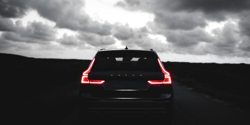 red car on black asphalt road under gray cloudy sky