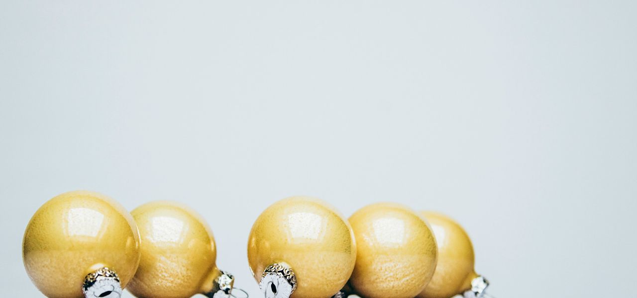 six gold Christmas baubles on white wooden surface