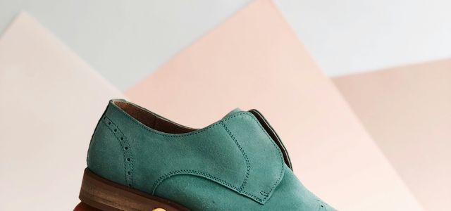 unpaired green leather shoe on top of white box