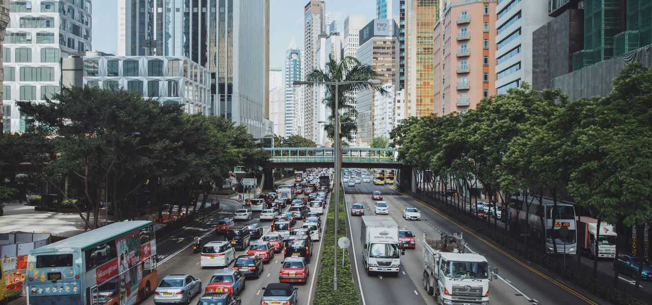 vehicles traveling on road between buildings during daytime
