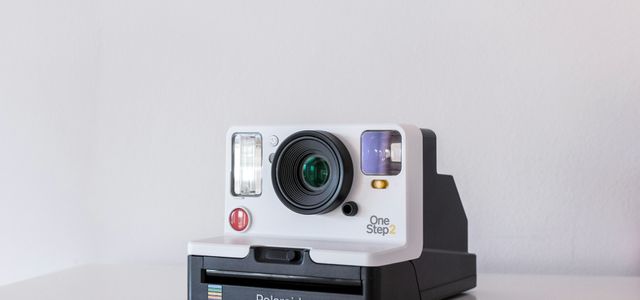 white and black Polaroid One Step 2 instant camera on white board