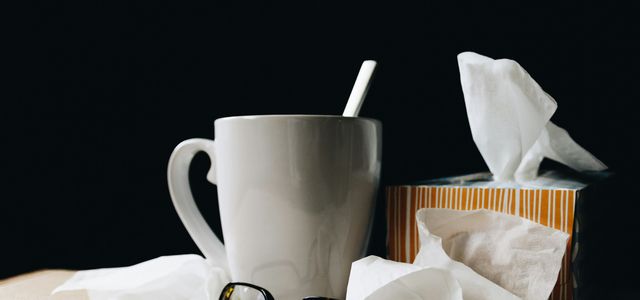 white ceramic mug on white table beside black eyeglasses