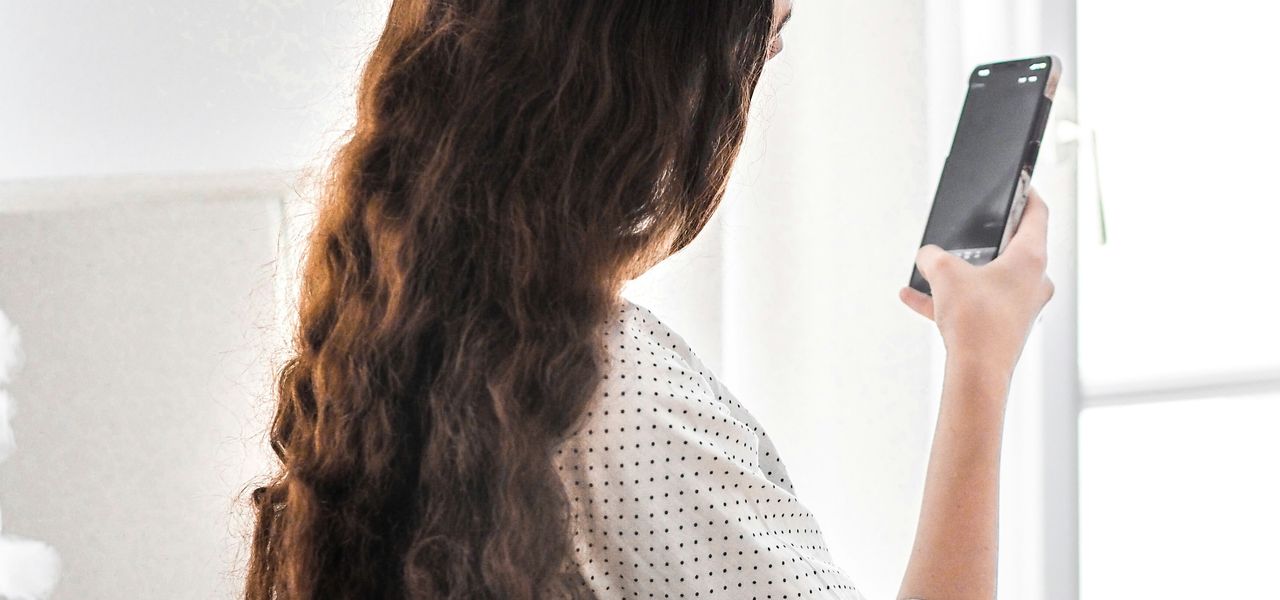 woman in white and black long sleeve shirt holding silver smartphone