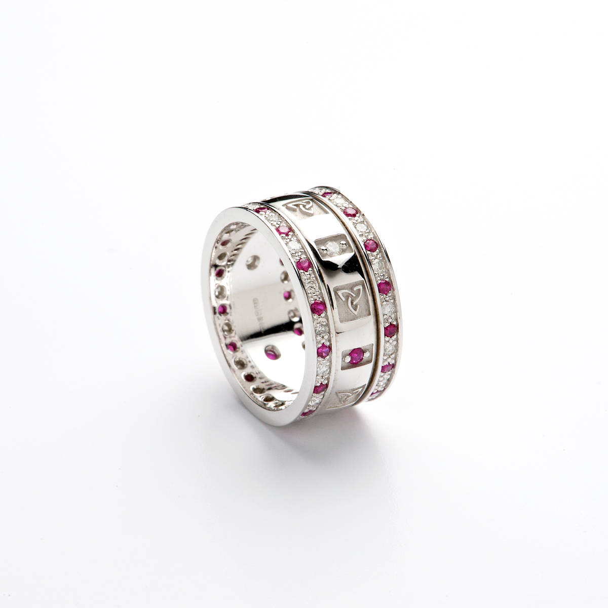 14ct white gold ladies wedding band with Celtic Trinity Knot windows and alternating diamonds and rubies. 

Centre contains 3 diamonds and 3 rubies and heavy raised Celtic Trinity Knot windows. 

Rim channel-set with diamonds and rubies also.

Width: 8.3 mm