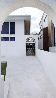 Brick archway framing a stone tiled walkway.