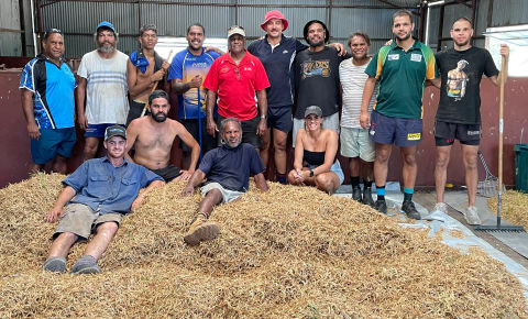 group of people sitting on pilessof wattle seed