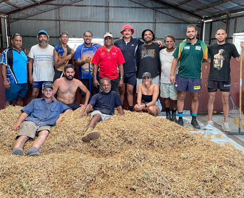group of people sitting on pilessof wattle seed