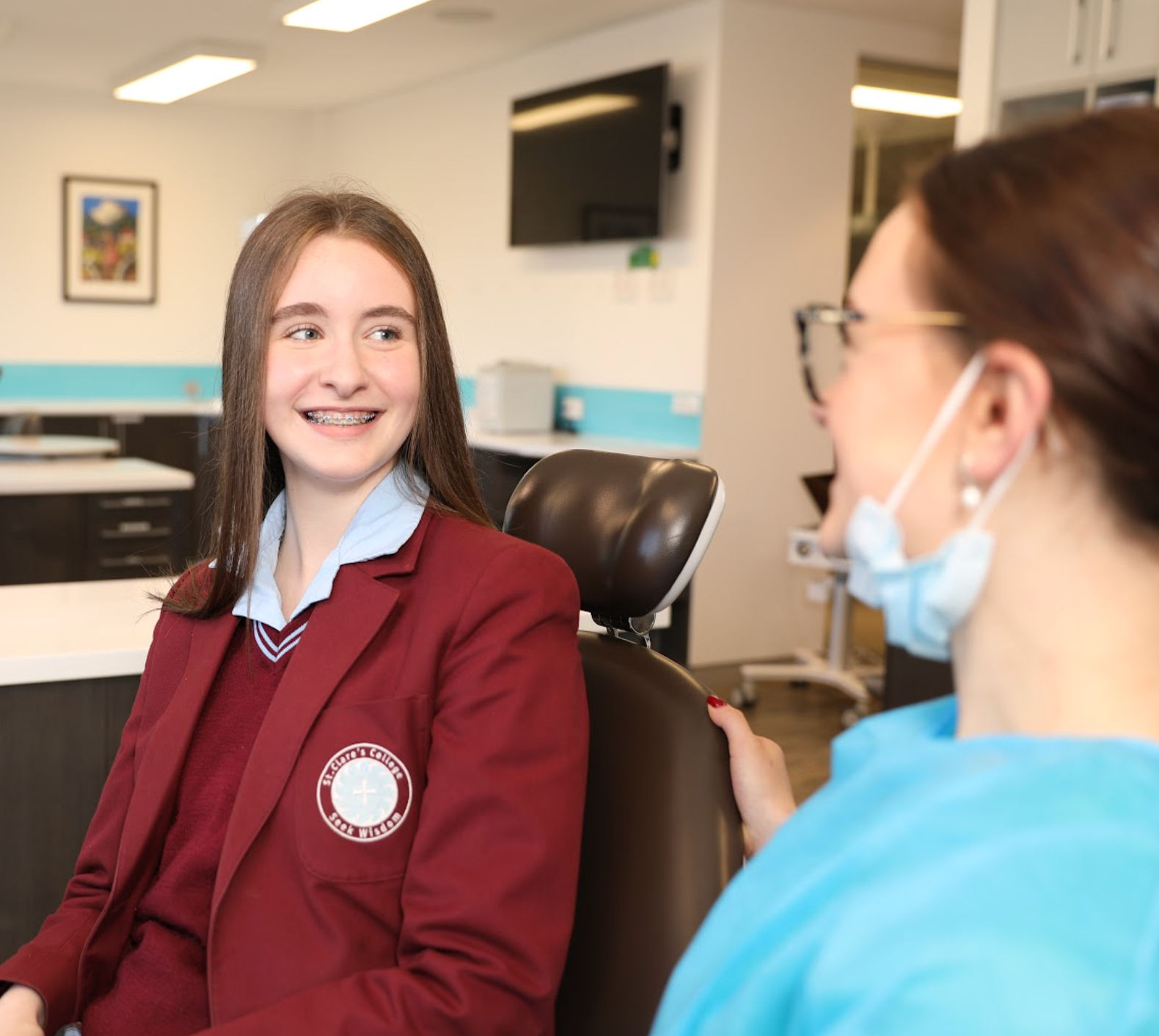 Teenage girl with braces smiling at dental pricatitioner