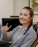 Teenage girl holding retainer smiling at camera