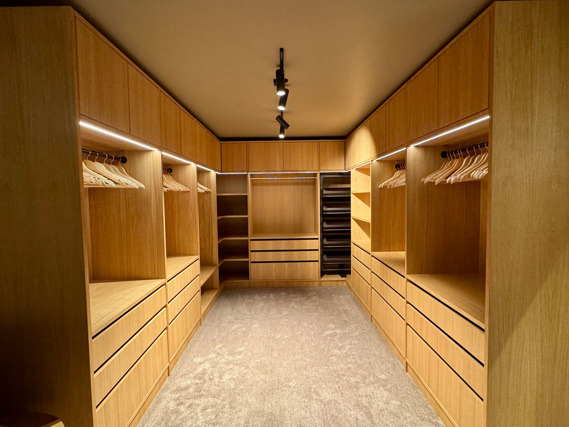 Skreddersydd walk-in garderobe i heltre med integrert belysning og praktisk oppbevaring