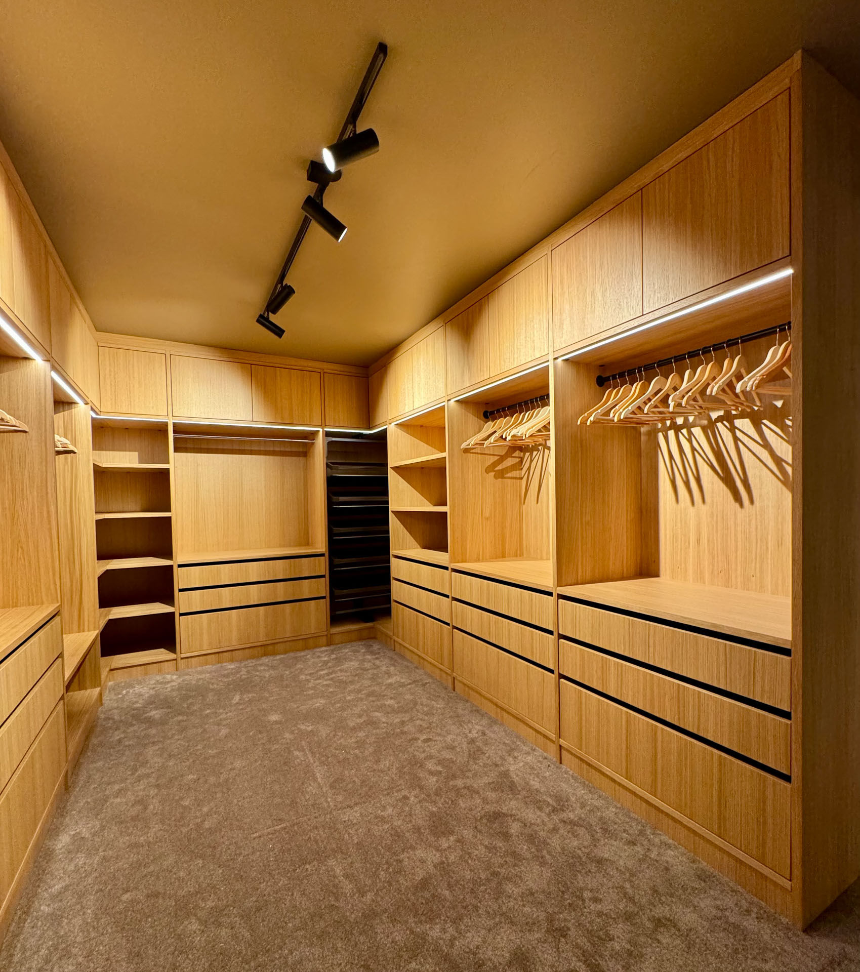 Skreddersydd walk-in garderobe i heltre med integrert LED-belysning, heng, skuffer og hyller