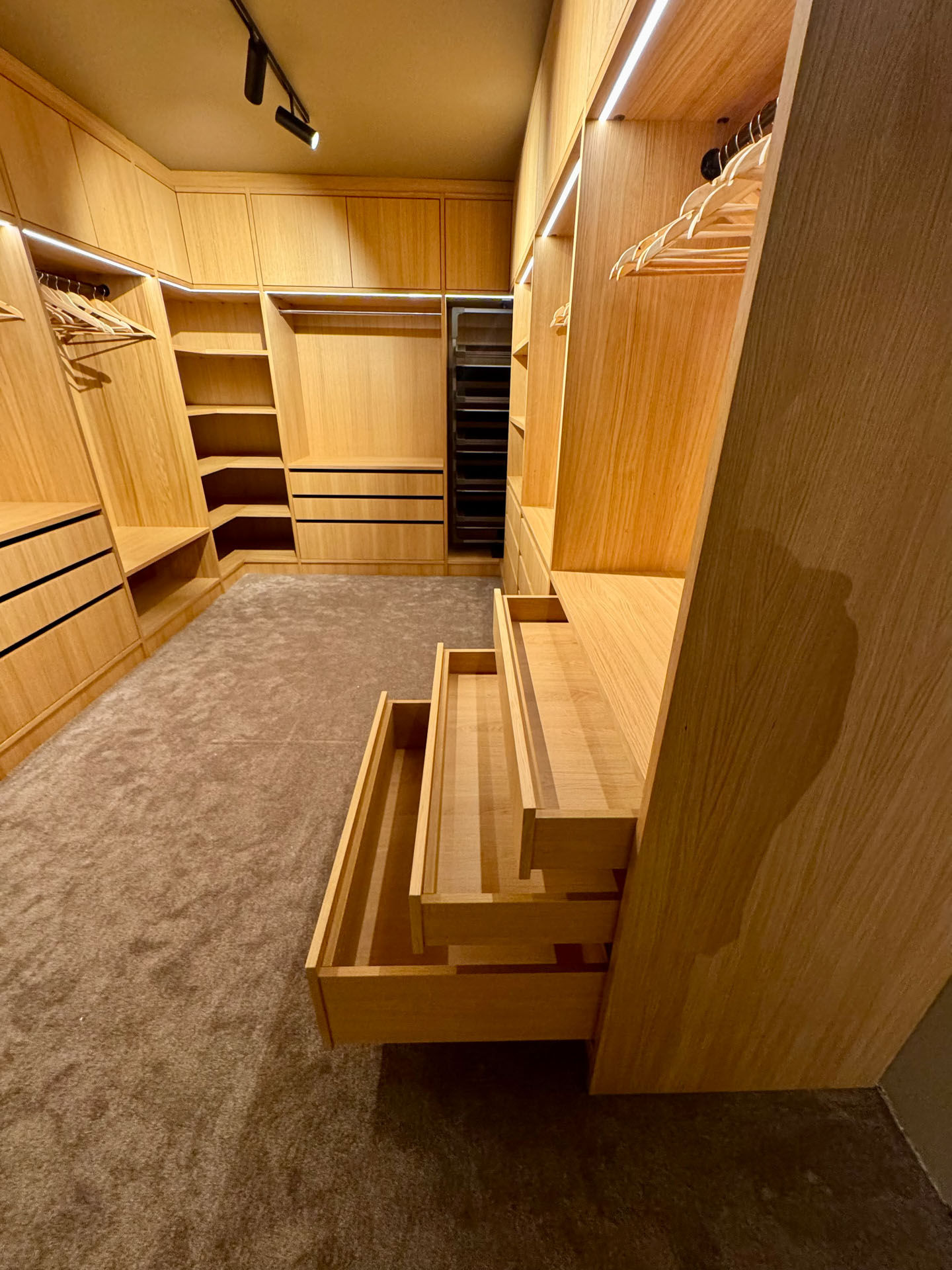 Detaljbilde av skreddersydd walk-in garderobe i heltre med uttrekkbare skuffer, heng og integrert belysning levert av Tromsdalen Bygg