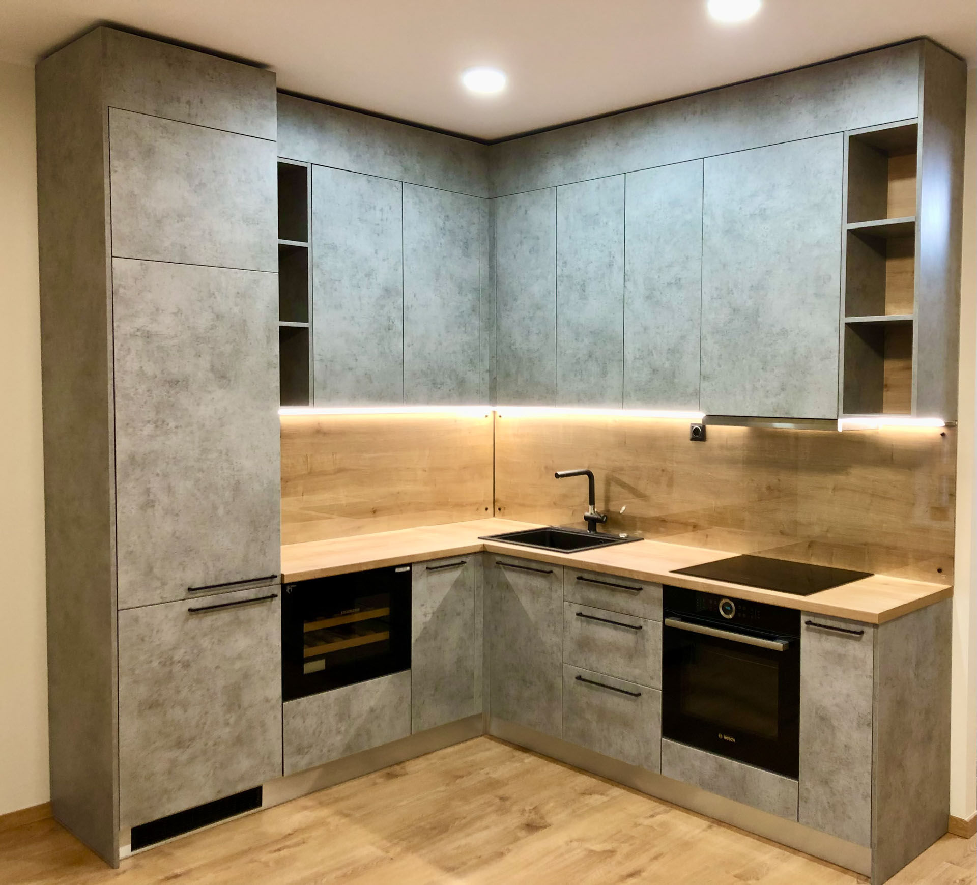 Skreddersydd hjørnekjøkken med grå betonginspirerte fronter, heltre benkeplate og integrert belysning levert av Tromsdalen Bygg