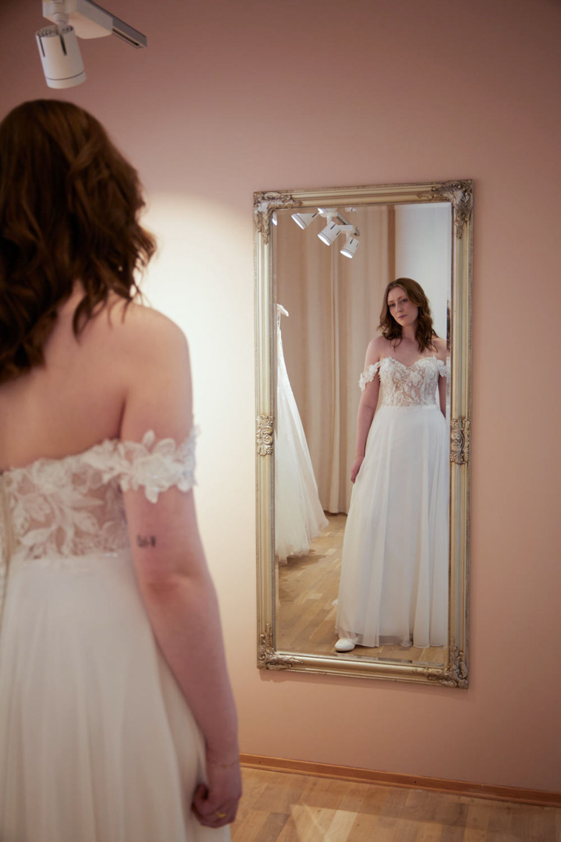 Brud ser på brudekjolen sin i speilet