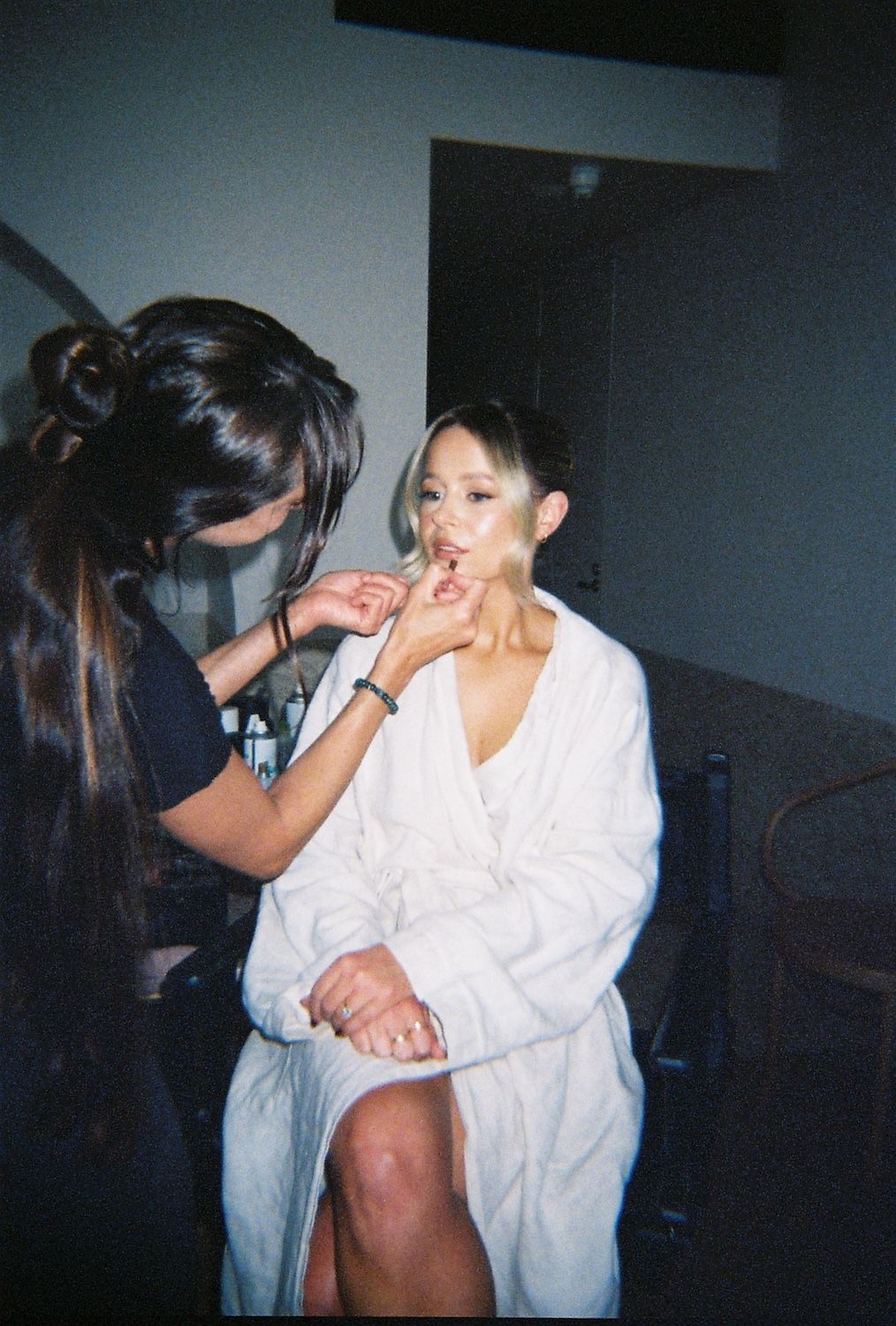 A grainy film style image of a bride having her make up applied.