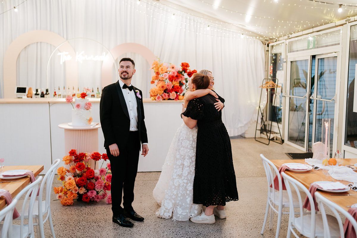 Couple hug wedding stylist Paradise Hunter after the reception room reveal.