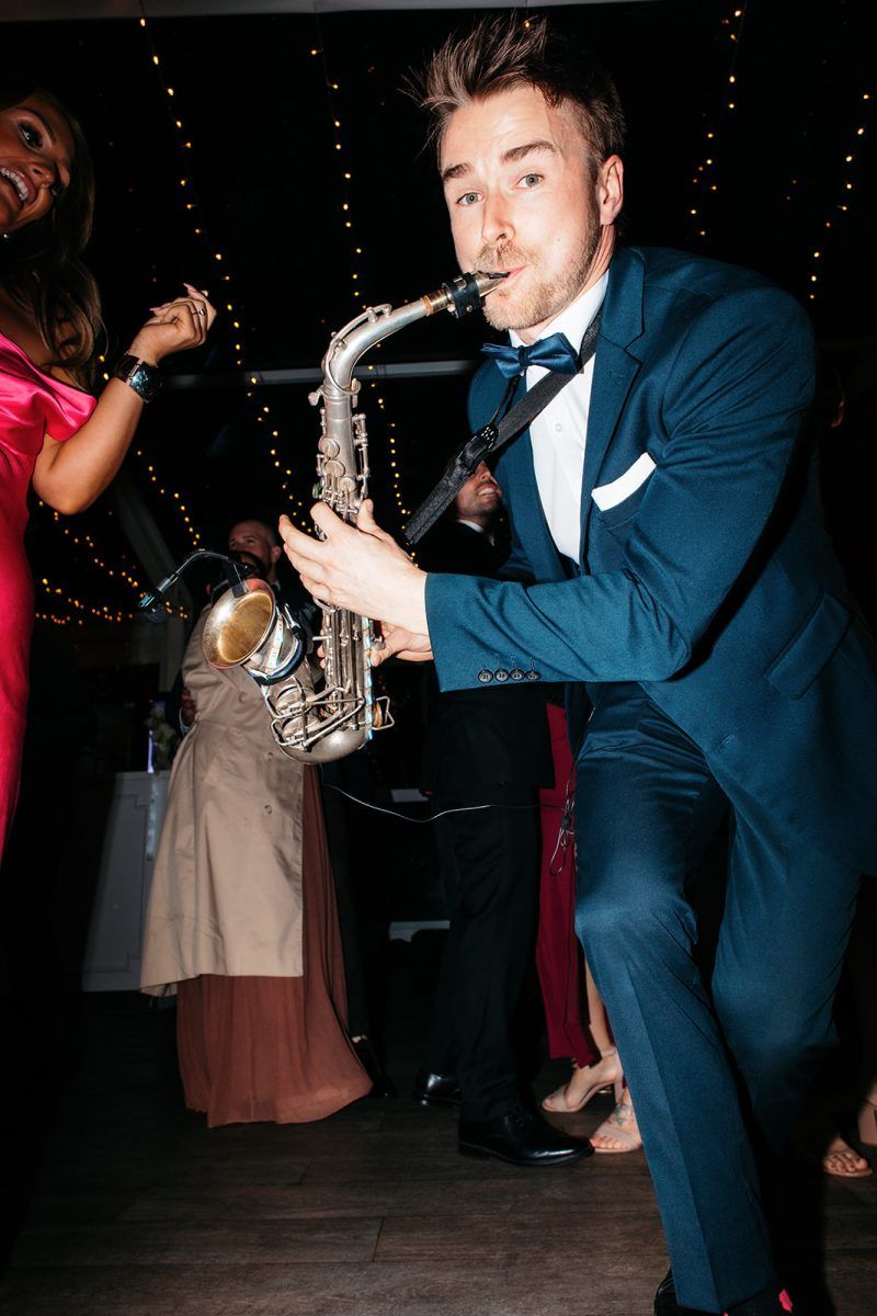 Wedding Sax Player leans in to camera on dance floor