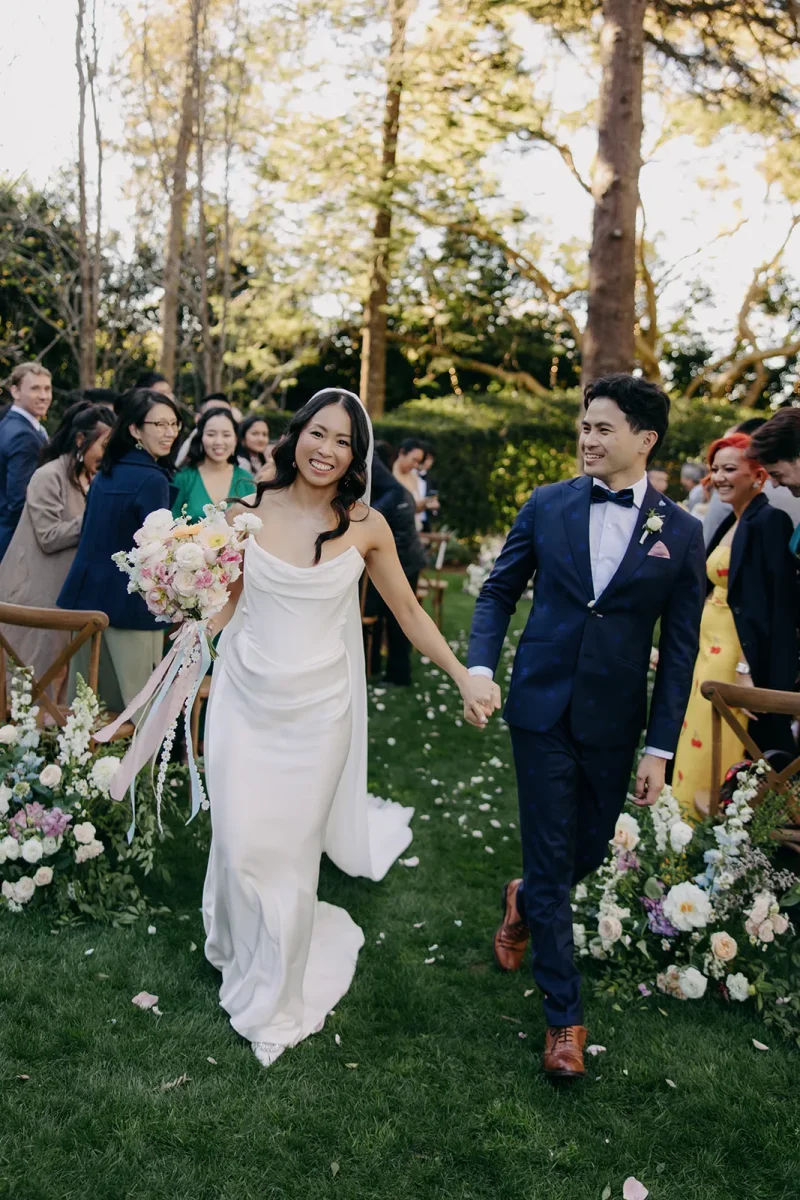A couple smile as they walk back down the aisle at their wedding ceremony.