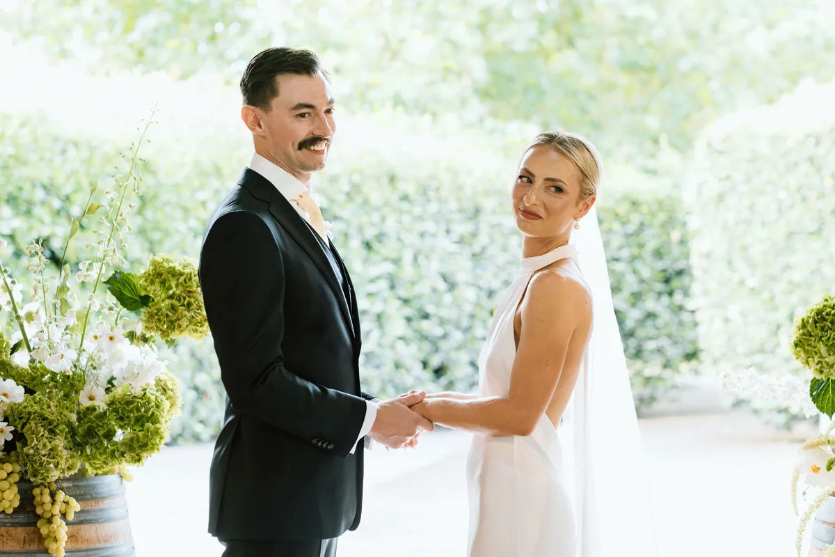 A couple hold hands during their wedding ceremony.