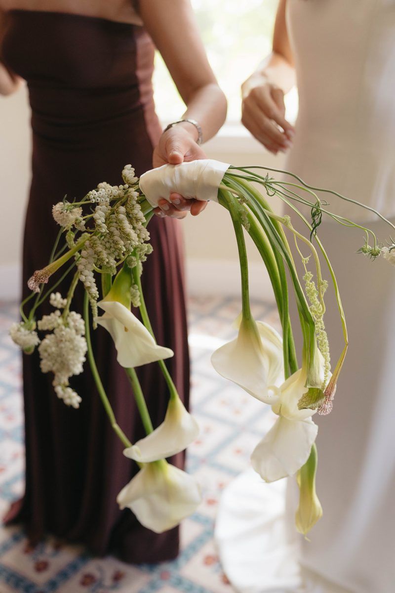 A close up of a handbag bouquet of calla lillies.