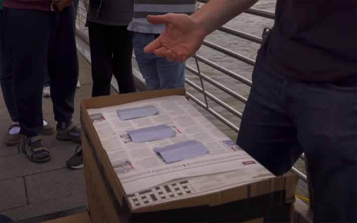 A street performer engaging a crowd with the 3 Card Monte trick.
