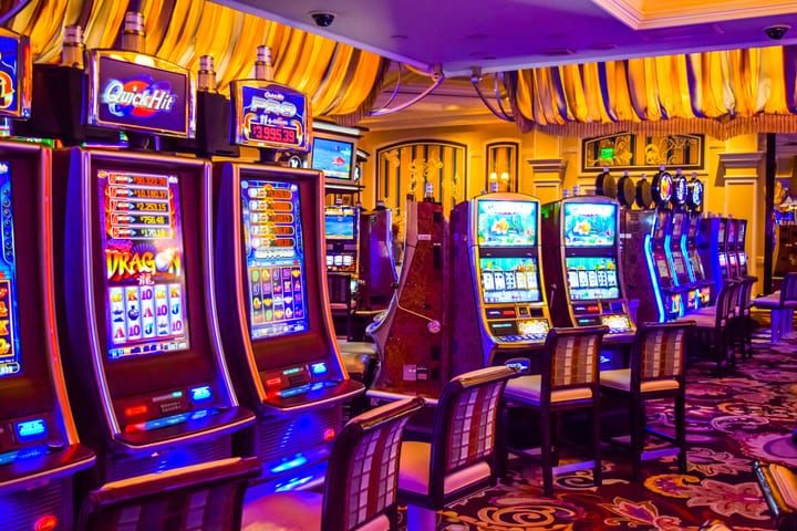 A row of brightly lit slot machines in a modern casino.