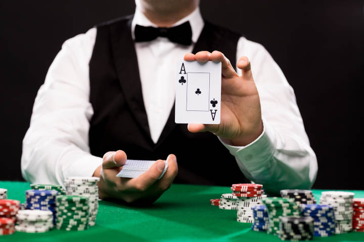 Close-up of a blackjack dealer's hands on a gaming table.
