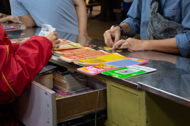 Close-up of a person's hands scratching a lottery ticket.