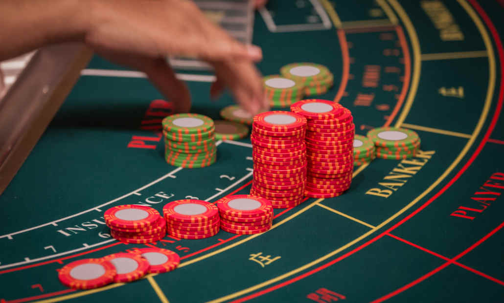 A dealer at a baccarat table handling cards.