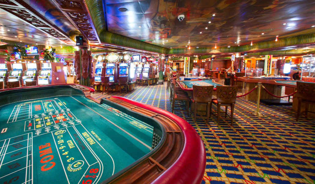 A busy casino floor with many people playing slots and table games.