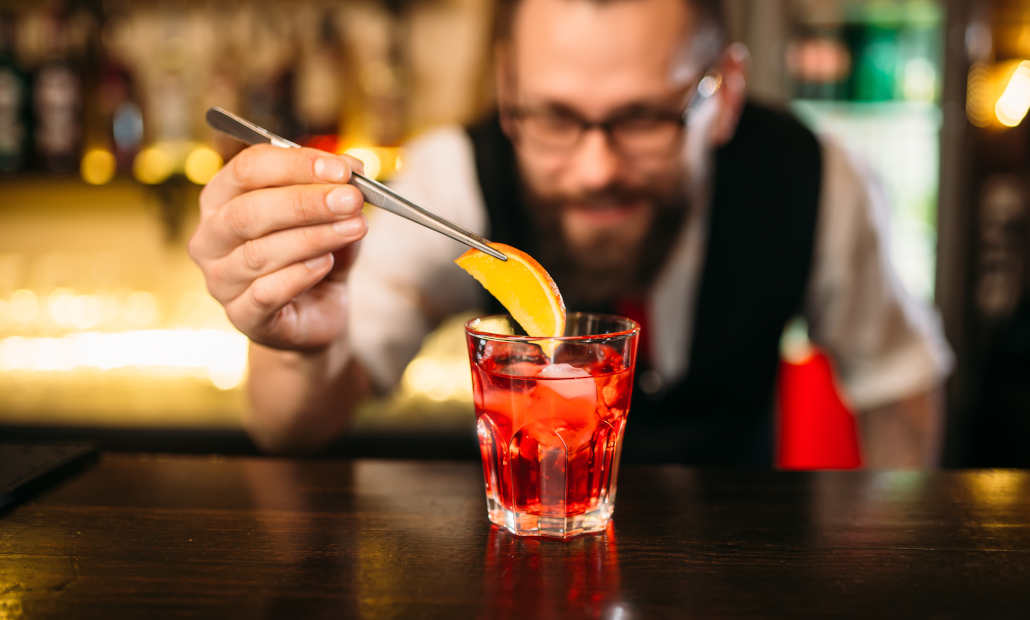 Colorful cocktails and mocktails lined up on a bar for a party.