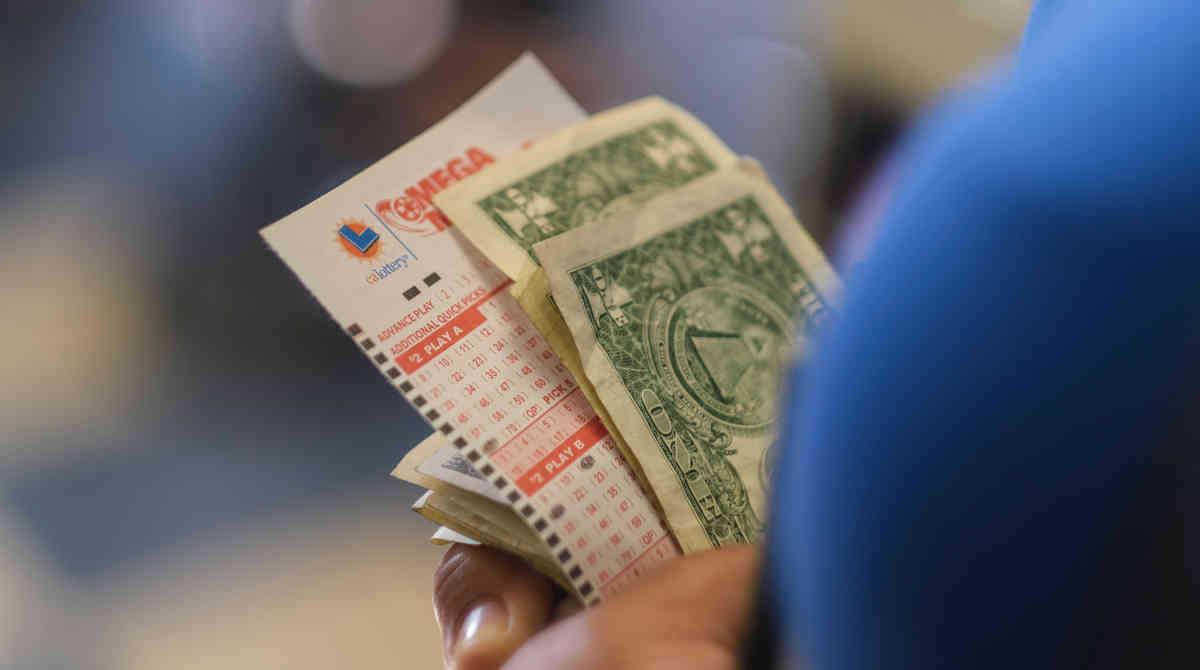 A person holding lottery tickets, symbolizing the advantages of group play.