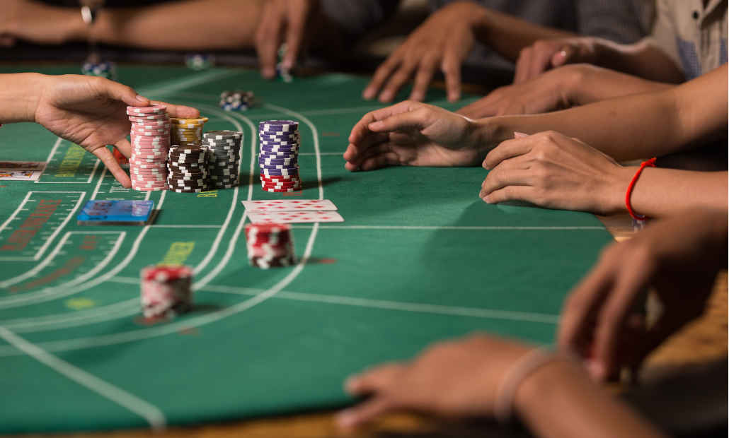 Player making a bet at a baccarat table in a casino.