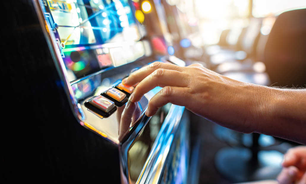 A person playing a slot machine in a casino setting.