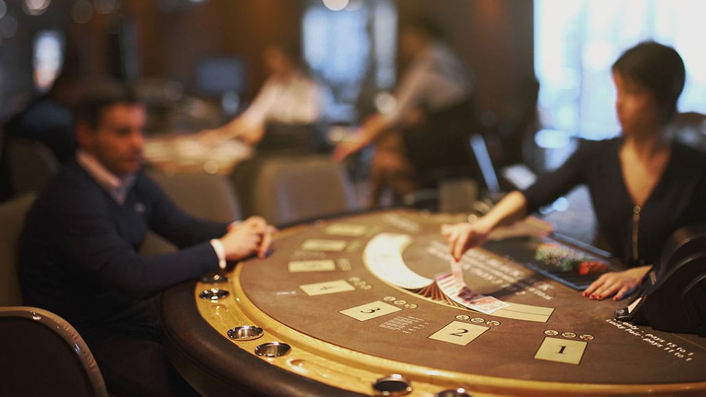 A casino dealer at a poker table with players.