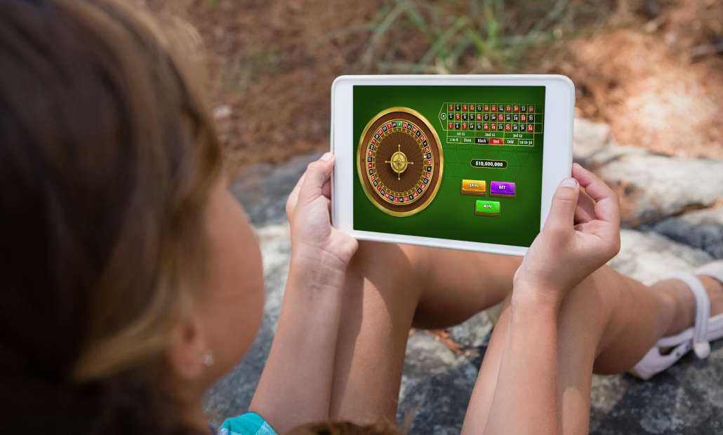 A person using a laptop with casino chips and cards, illustrating online casino tips.