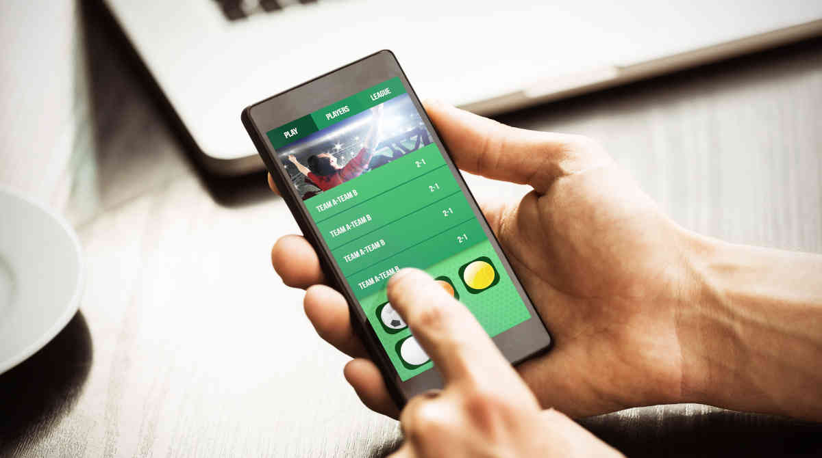 A person holding a smartphone showing a successful bet notification.