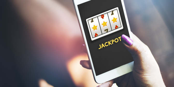 Hand holding a smartphone showing a real money slot game.