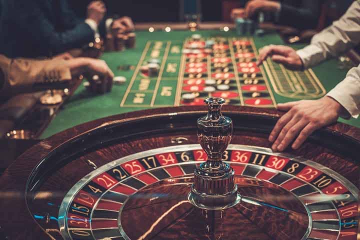 Hands holding playing cards over a casino table, representing playing with a casino bonus.