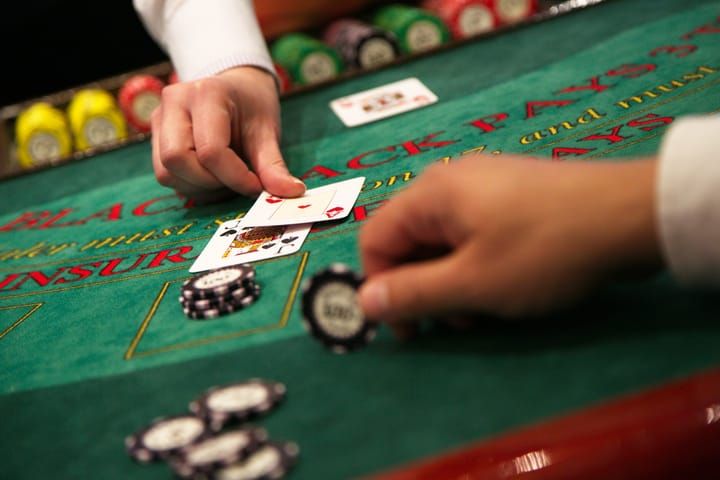 A player looking at their cards at a blackjack table, contemplating their next move.