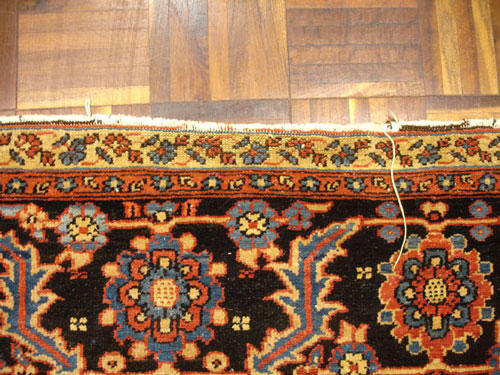 An antique Persian rug with unravelling fringe before repair.