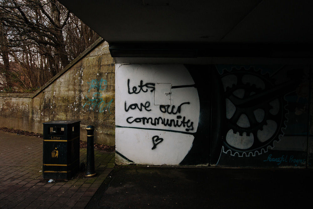 An underpass wall graffitied with "Let's love our community."