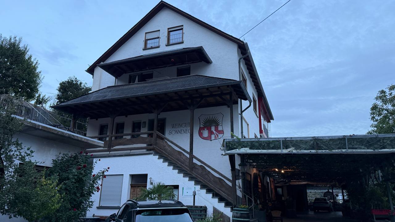 Weingut Sonneneck building — white gable roof, covered entrance, parking