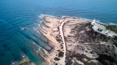 Coastal Majesty: A breathtaking aerial view captures the beauty of a rugged shoreline, a majestic lighthouse, and a serene beach, inviting tranquility and adventure. Alicante, Spain