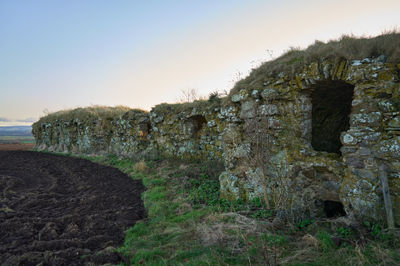 The ruins Barnes Castle in the fields of Scotland under a blue sky