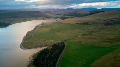 aerial picture of grassy meadows and a water reservoir at twilight