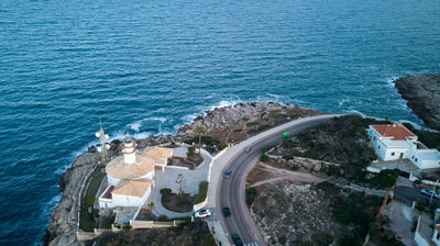 An aerial view of a city on the coast of spain. A picturesque lighthouse perched atop a rugged cliff