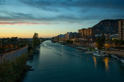 Cullera, Valencia, Spain - 03.13.2023 A bustling cityscape under a dreamy sky. A boat meanders through the river, contrasting with the vibrant blue. 