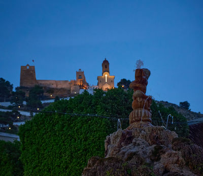 Cullera Castle: Majestic Castle and Enchanting Fountain Embrace Moonlit Splendor, Commanding a Mesmerizing View of City Lights and Romance